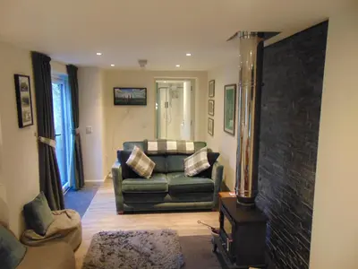 a living room with a couch and a fireplace at Dreamwood Cottage, Loch Lomond, Luxury Apartment. in Glasgow