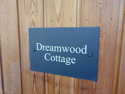 a blue sign that says dreamwood cottage on a wooden wall at Dreamwood Cottage, Loch Lomond, Luxury Apartment. in Glasgow