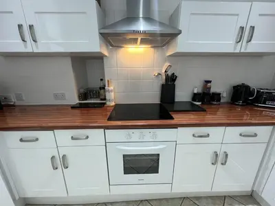 a kitchen with white cabinets and a stove top oven at Hollybank Cottage in Lochgoilhead