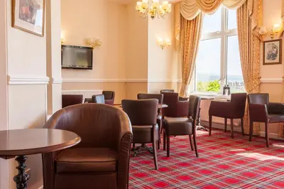 a waiting room with tables and chairs and a window at SGE Esplanade Hotel in Dunoon