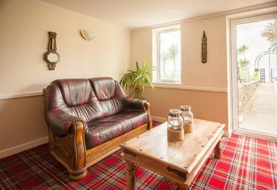 a living room with a leather chair and a coffee table at SGE Esplanade Hotel in Dunoon