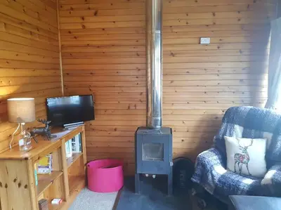 a living room with a woodburning stove in a room at Pine Cabin, Strathyre. A cosy escape from it all. in Strathyre