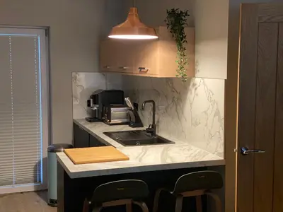 a kitchen with a sink and a counter with chairs at Lovely 3 bed with jacuzzi, close to airport, driveway, wifi in Edinburgh