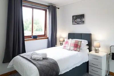 a bedroom with a white bed and a window at Bothwell Court Apartments in Dunfermline