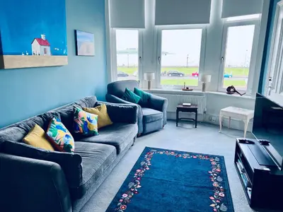 a living room with blue walls and a blue couch at Seaview one bedroom apartment in centre of Largs in Largs