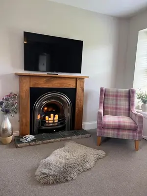a living room with a fireplace with a tv and a chair at Menstrie Castle Stay in Stirling