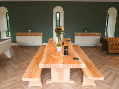 a wooden table in a living room with a table at Coach House Ratho Park Steading in Ratho