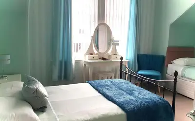 a bedroom with a bed and a mirror and a chair at Dawn Break Guest House in Largs