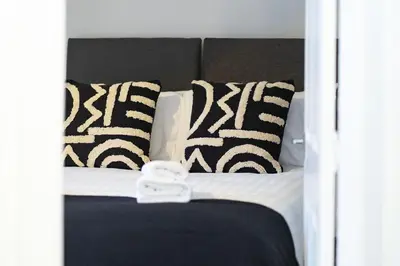 a bed with black and white pillows on it at Cross Road Apartment in Paisley