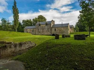 an old stone building on a grassy hill with a field at Stunning Edinburgh 1820s stables converted house in Ratho