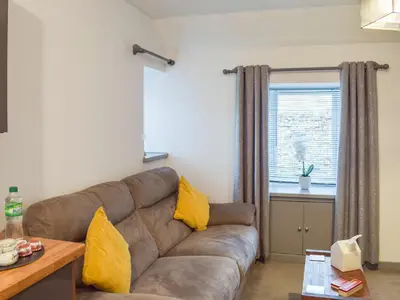 a living room with a brown couch and a window at The Cottage in Girvan