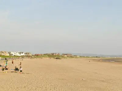 a group of people sitting on a beach at The Cottage in Girvan
