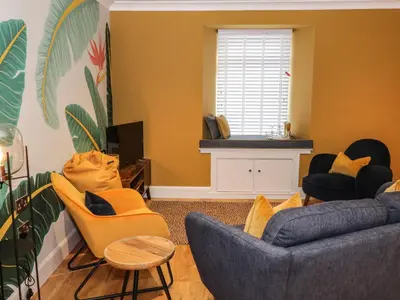 a living room with yellow chairs and a couch at Feus Holiday Cottage in Auchterarder