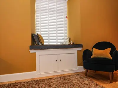 a room with a white cabinet and a chair and a window at Feus Holiday Cottage in Auchterarder