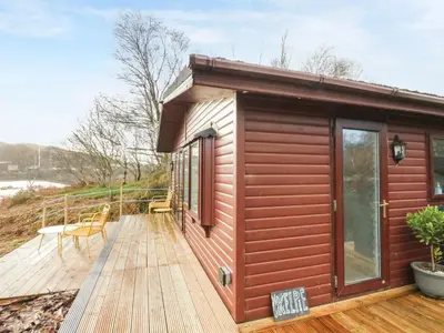 a cabin with a deck with a table and chairs at Kelpie in Lochgilphead