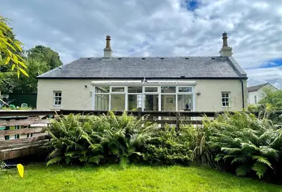 a white house with a large window in the yard at Kevington Cottage in Hunters Quay
