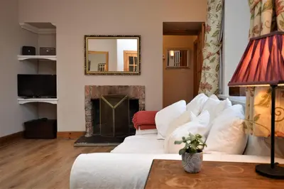 a living room with a white couch and a fireplace at Kevington Cottage in Hunters Quay