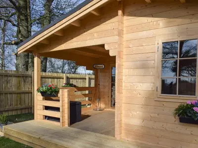 a wooden shed with a deck with flowers at Pinewood Cabin in Saline
