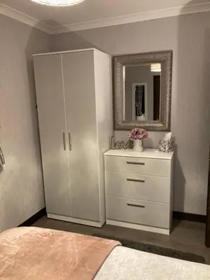 a bedroom with a white cabinet and a mirror at Machrie Cottage, Oban, in Oban