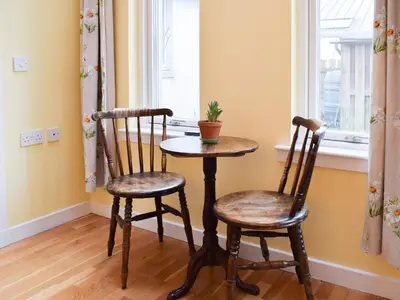 a table and two chairs in a room with a window at Puddingstone Cottage in Gartmore