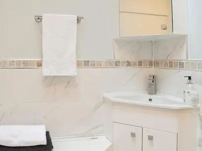 a white bathroom with a sink and a mirror at Puddingstone Cottage in Gartmore