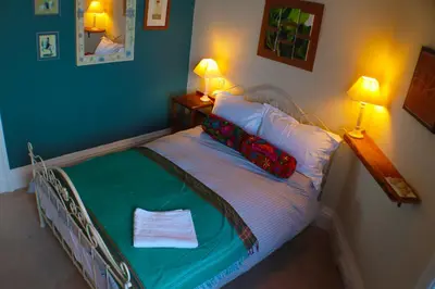 a bed in a room with two lamps and a bed with a green blanket at Grand top floor apartment in the Royal Bank House in Maybole