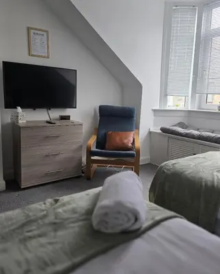 a bedroom with a tv and a chair and a bed at Castleblair Snug - Entire Flat in Dunfermline in Dunfermline