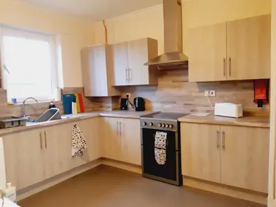 a kitchen with wooden cabinets and a stove top oven at Carvetii - Vincent House - Large 3 bedroom apartment with on-site parking in Fife