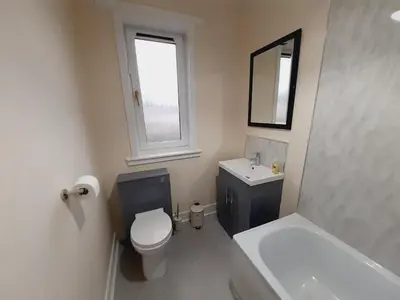 a bathroom with a toilet and a sink and a mirror at Carvetii - Vincent House - Large 3 bedroom apartment with on-site parking in Fife