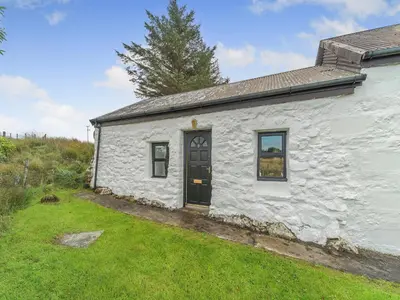 a small white cottage with a black door at The Bothy - Uk37414 in Bunessan