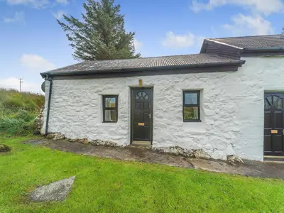 a white cottage with black doors and a yard at The Bothy - Uk37414 in Bunessan