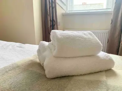 a pile of white towels sitting on top of a bed at Allerton - Victorian Character Home in Stirling in Stirling