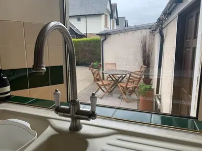a kitchen sink with a view of a patio with a table at Allerton - Victorian Character Home in Stirling in Stirling