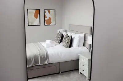 a bedroom with a mirror next to a bed at JOIVY Luxurious Apt on Notable George Street in Edinburgh