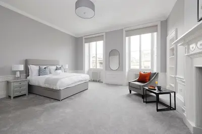 a white bedroom with a bed and a chair at JOIVY Luxurious Apt on Notable George Street in Edinburgh