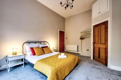 a bedroom with a bed with a yellow bedspread at Stylish & Spacious 3 Bedroom Apt in Finnieston, West End in Glasgow