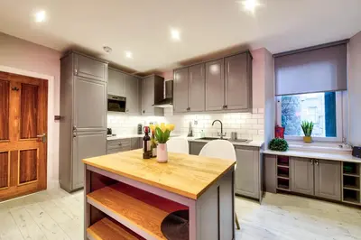 a kitchen with gray cabinets and a wooden counter top at Stylish & Spacious 3 Bedroom Apt in Finnieston, West End in Glasgow