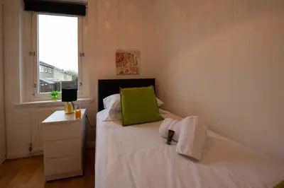 a bedroom with a bed with a green pillow and a window at PREMIER - Chapel House with Driveway! in Cleland