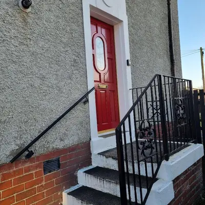 a red door on a brick building with stairs at PREMIER - Chapel House with Driveway! in Cleland