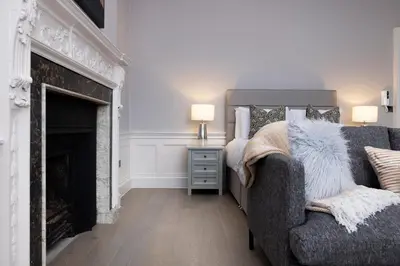 a living room with a couch and a fireplace at JOIVY Modern Studio in New Town, on Historic George Street in Edinburgh