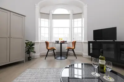 a living room with a table and chairs and a tv at JOIVY Modern Studio in New Town, on Historic George Street in Edinburgh