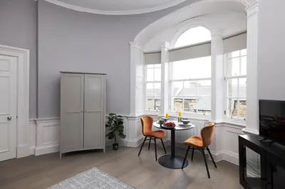 a dining room with a table and chairs and a window at JOIVY Modern Studio in New Town, on Historic George Street in Edinburgh