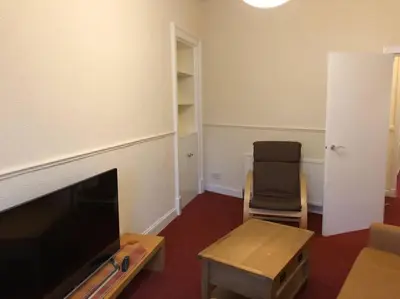 a living room with a flat screen tv and a chair at Pier Head in Largs