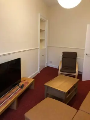 a living room with a tv and a table and a chair at Pier Head in Largs