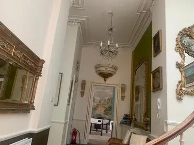 a hallway with a staircase with a chandelier and a mirror at 2 Chester St in Edinburgh