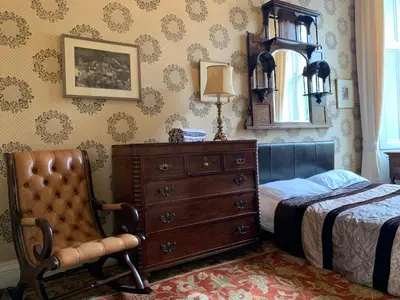 a bedroom with a dresser and a bed and a chair at 2 Chester St in Edinburgh