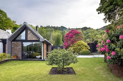 a house with a garden with a tree in the yard at Roselea Cottage in Luss