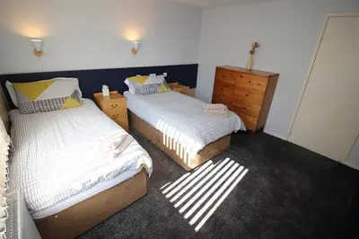 a bedroom with two twin beds and a dresser at Allandale House in Brodick