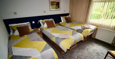 a bedroom with two beds with a person sleeping on them at Allandale House in Brodick