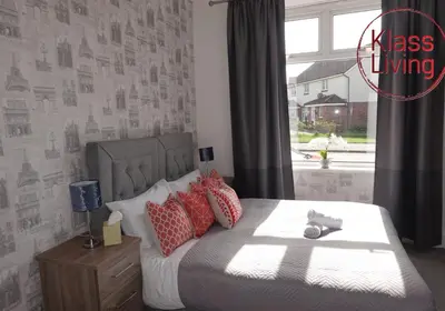 a bedroom with a bed with red pillows and a window at Mossend Apartment by Klass Living Bellshill in Mossend